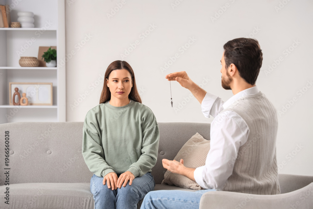 Obraz premium Young woman sitting on sofa during hypnosis session at psychologist's office