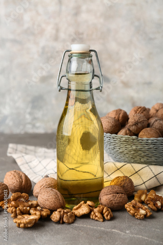 Cuadro en lienzo Bottle of fresh walnut oil and nuts on grey background