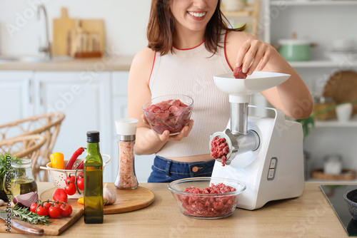 Young woman using meat grin...
