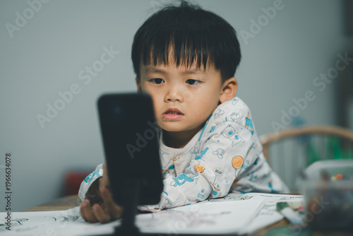Toddler Watching Smartphone While Drawing at Table