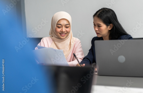 Foto Two diverse asian businesswomen in hijab and suit having serious discussion over