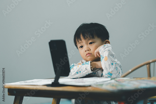 Toddler Watching Smartphone While Drawing at Table