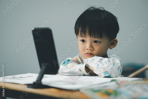 Toddler Watching Smartphone While Drawing at Table