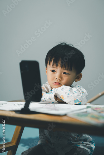 Toddler Watching Smartphone While Drawing at Table