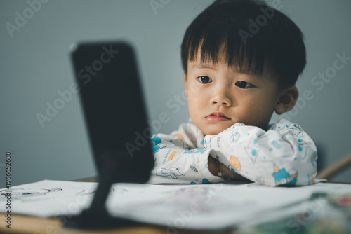 Toddler Watching Smartphone While Drawing at Table