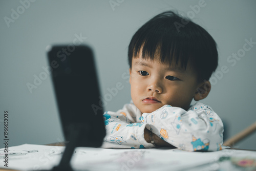 Toddler Watching Smartphone While Drawing at Table
