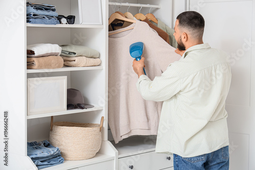 Young man steaming jumper i...