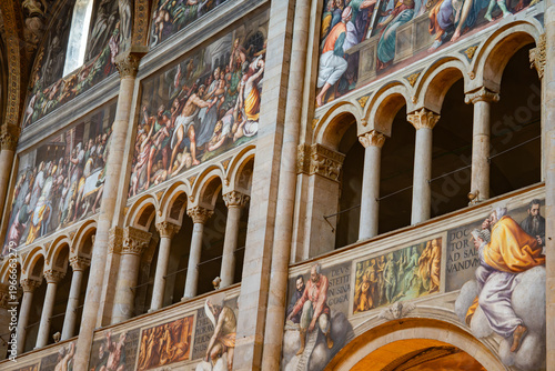 View of the upper gallery arches and narrative frescoes along the nave of Parma Cathedral, Italy 06.01.2026