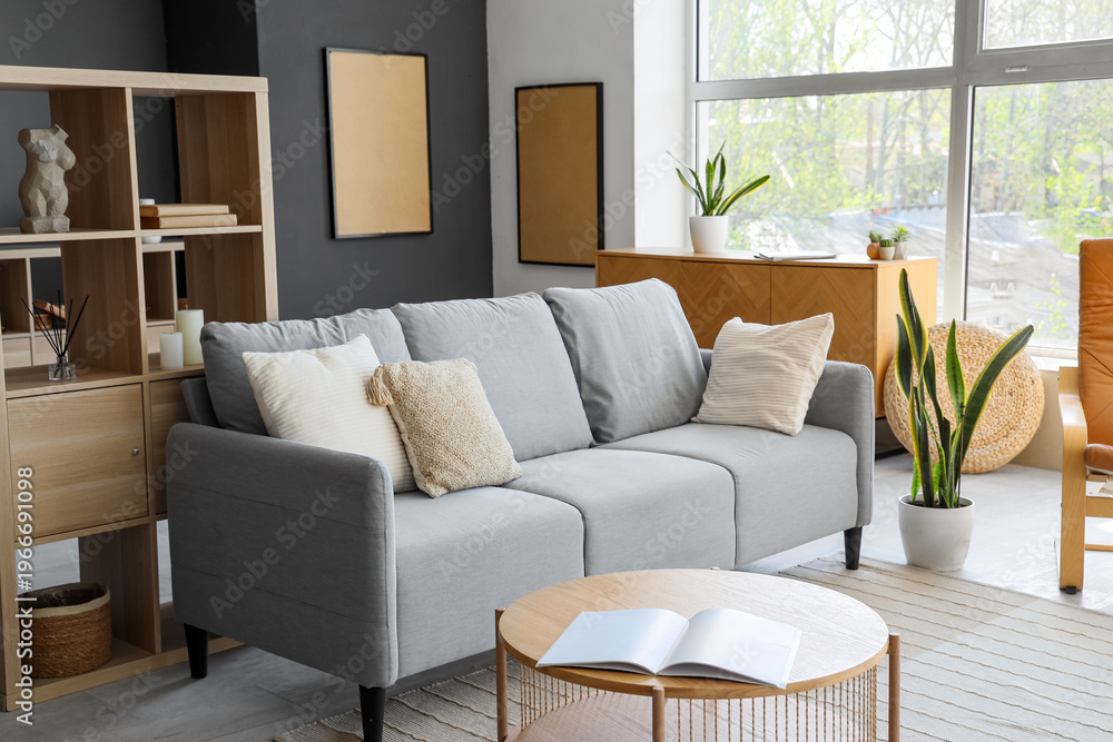 Fototapeta premium Interior of modern living room with grey sofa and shelf unit