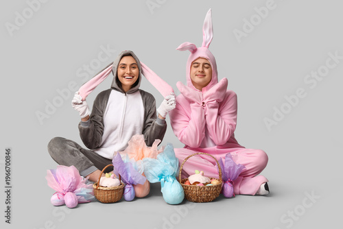 Beautiful young couple in bunny costume with Easter baskets and gift eggs sit...