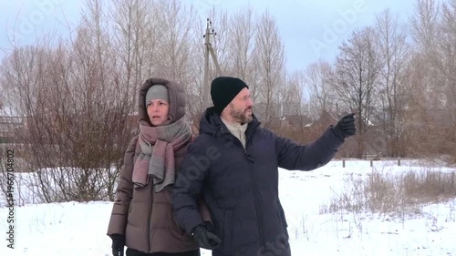 Mature Couple in Warm Winter Clothing Enjoying a Walk and Talking in Snowy Park