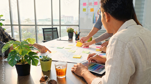 Collaborative design team brainstorming innovative ideas with sticky notes and digital color palettes in a modern.
