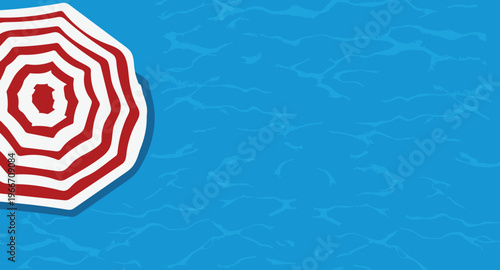 Overhead view of a red and white striped beach umbrella on blue background