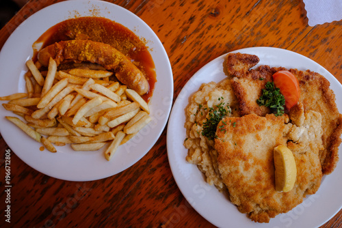The photo shows traditional Bavarian food including schnitzel served with potato salad on a plate. Meat dish with side, indoor setting, restaurant style, close-up view, natural light, European cuisine