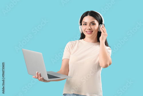Photos Female programmer in headphones with laptop on blue background