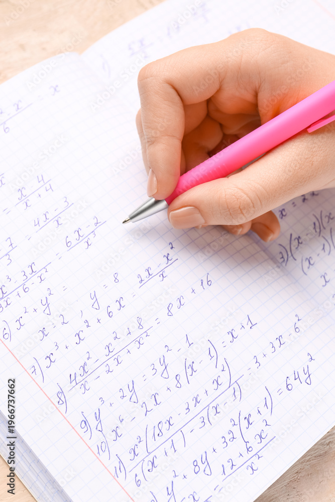 Fototapeta premium Woman writing maths formulas in copybook with pen, closeup