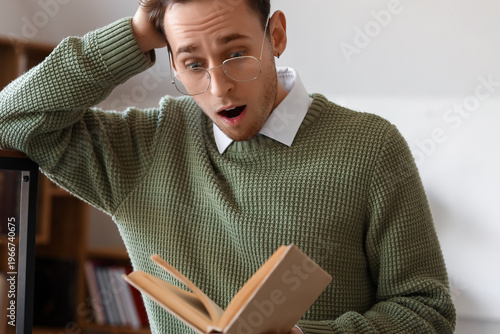 Shocked young man reading b...