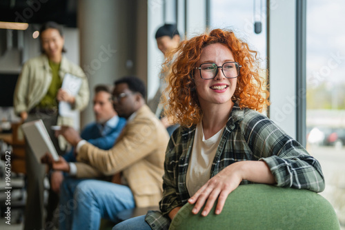 Smiling redhead woman student working in modern office startup