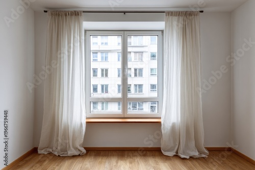 Bright room with sheer curtains framing a window showing a modern building.
