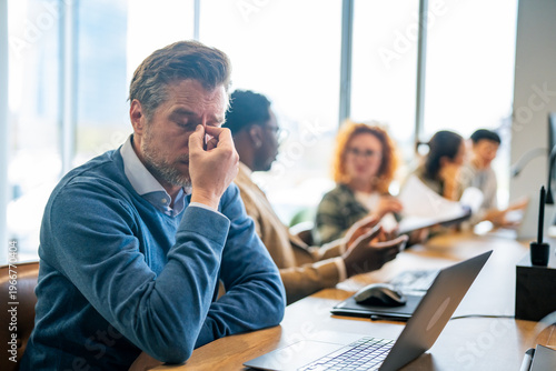 Stressed businessman suffering headache and burnout at office desk