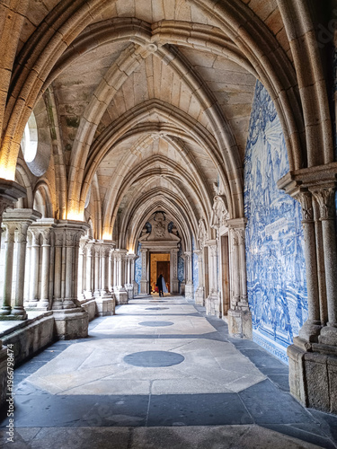 Corridor with Gothic arches and blue Portuguese tiles with a door at the end in Porto Cathedral, PORTUGAL