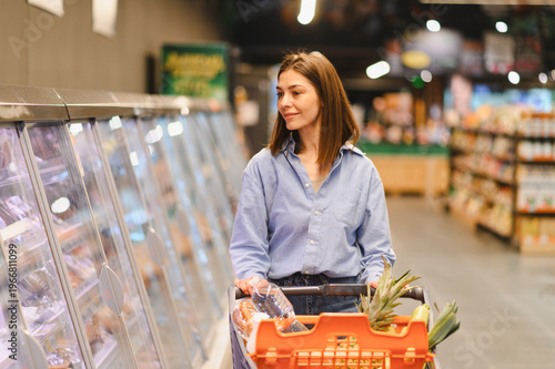 Photos Woman shopping for groceries in supermarket freezer aisle