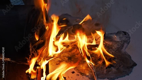 A melted plastic electric kettle engulfed in flames, with the fire brightly illuminating its surface and rising upward. a dangerous situation, with dense tongues of fire covering its body.