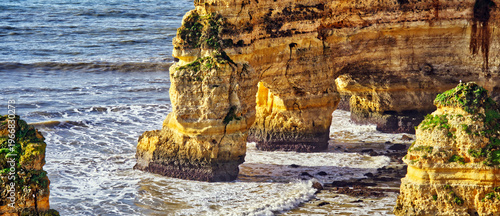 Algarve coastline with natural rock arches and sea stacks forming a scenic landscape on a sunny day