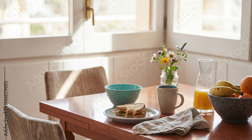 Tableau sur toile Healthy and fresh breakfast scene on a sunlit wooden table with a sandwich and fruits near a window