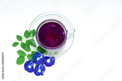 Foto Top View - Butterfly pea flower herbal tea in a clear glass cup with vibrant blue petals and green leaves on white background