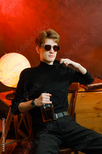 Confident young man in black turtleneck holding whiskey bottle.