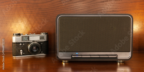 Quadro su tela A wireless Bluetooth speaker in a retro style and a vintage camera with warm lig