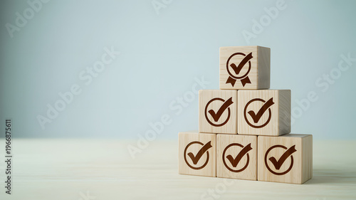Wooden blocks stacked in pyramid with checkmarks on each symbolizing success and verification