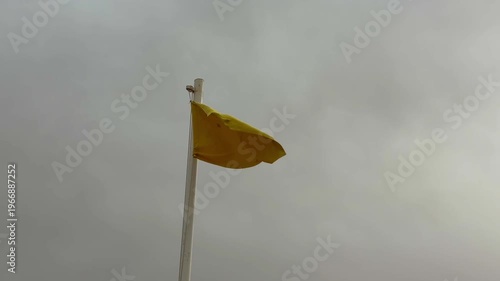 Flag Atop Pole Indicating Danger Amidst Turbulent Weather And High Surf Conditions