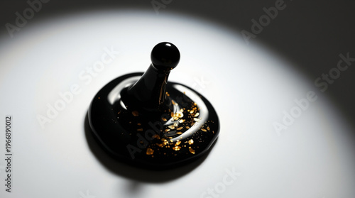 A black cylindrical object with a spherical top sits on a white plane, featuring a smooth reflective base sprinkled with