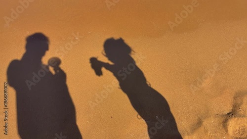 Sunset Shore Sharing Moments. Silhouettes On Sandy Shore With Ocean Waves And Warm Hues
