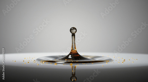 A dark drop impacts liquid surface, forming a crown with suspended transparent sphere, surrounded by golden particles, c