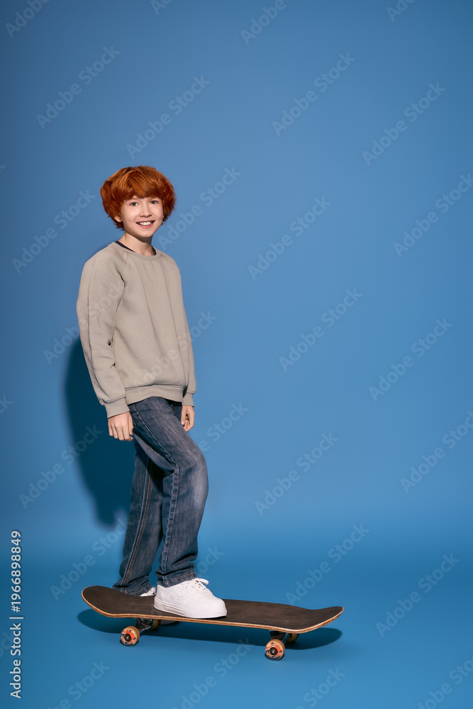 Naklejka premium Stylish boy enjoying a skateboard ride on a vibrant blue background