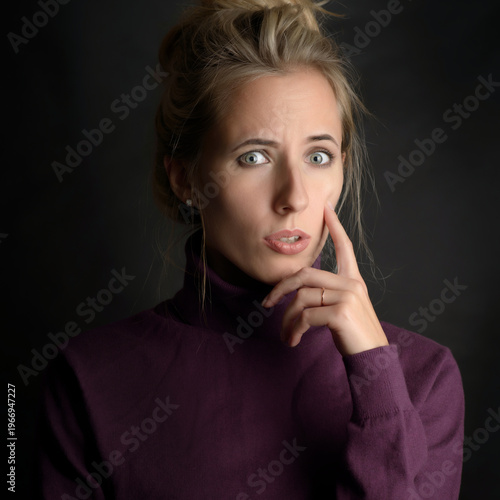 Elegant portrait of thoughtful woman in purple sweater with soft dramatic lighting.