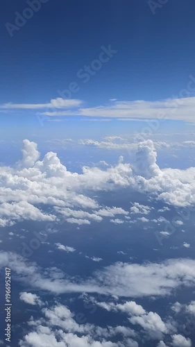 Vertical view of cumulus clouds at high altitude Fluffy clouds fill the frame creating a serene sky with natural light and atmospheric depth
