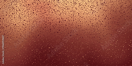 Macro view of many clear water drops and liquid bubbles on a smooth glass surface over a vibrant red and orange background with golden light