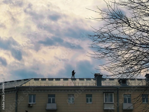 Foto Silhouette of a chimney sweep walking on a roof under a cloudy sky