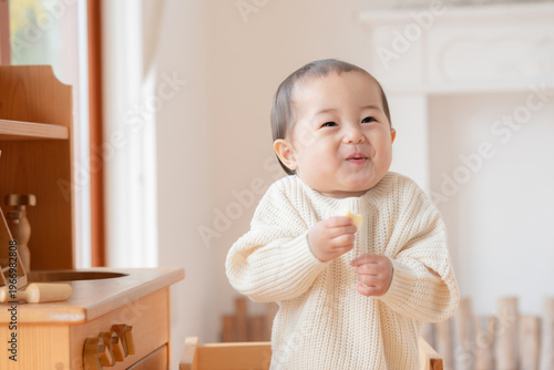 白いセーターを着て笑う１歳の子供