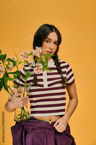 Young woman with pigtails delights in gardening while showcasing vibrant flowers indoors