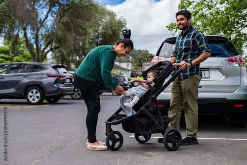 Kiwi parents with baby in stroller at parking lot 