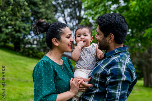 A couple with their child spending quality time together, standing closely at a park at daytime in New Zealand