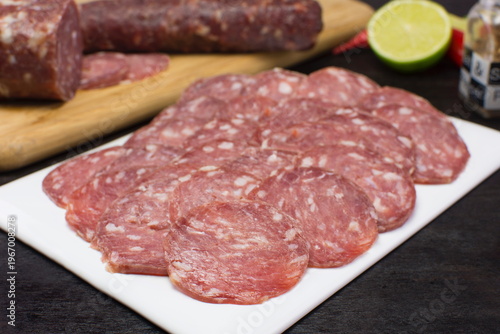 Sliced Italian Salami in a white plate in black background