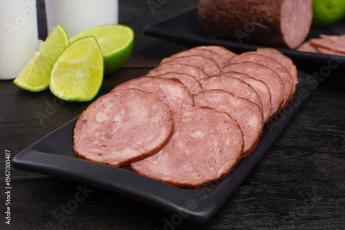 Sliced pepperoni in a white plate in black background