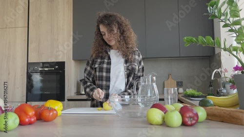 Curly Female Making Fresh Lemon Drink In Cozy Bright Home Kitchen