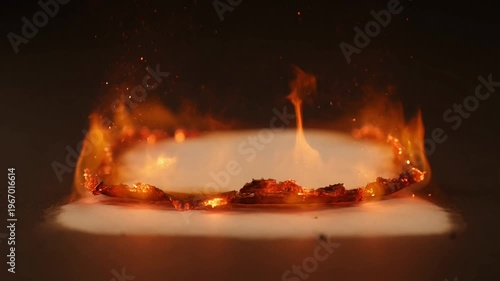Flames engulf a circle of fire on the ground at night